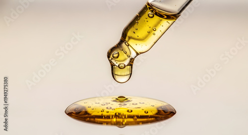 Wallpaper Mural Golden oil dripping from glass dropper onto surface with bubbles liquid pipette Torontodigital.ca