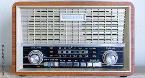 Photos Vintage wood-style retro radio receiver with analog tuning dial on wooden backgr