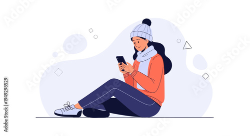 Young woman in winter clothes using smartphone while sitting on the floor
