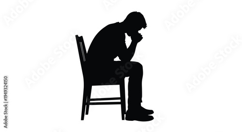 A solitary man sits head in hands a stark black silhouette