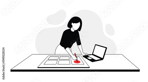 A female artist or designer marks a red circle on a storyboard at her desk next to a laptop.