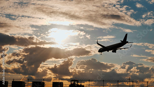 Passenger airplane landing at sunset in cloudy sky