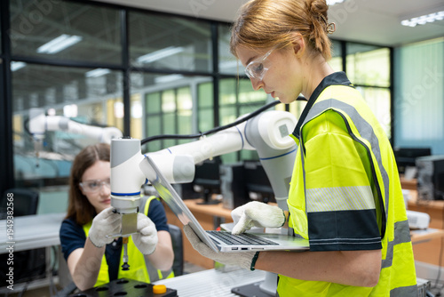 Cuadro en lienzo Professional female engineers using laptop to program and control collaborative robotic arm in modern industrial laboratory, focusing on smart factory automation and future robotics technology