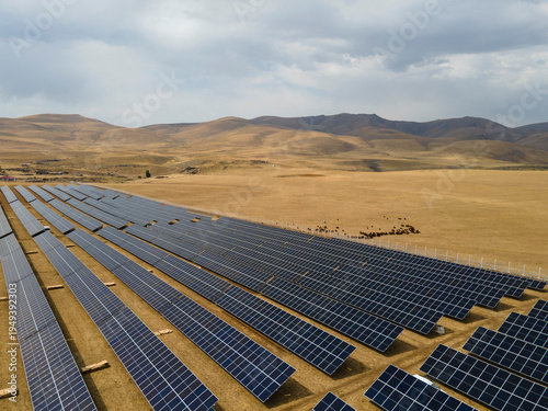 Drone view of a large solar panel construction site in an open field, showing renewable energy infrastructure and outdoor industrial work