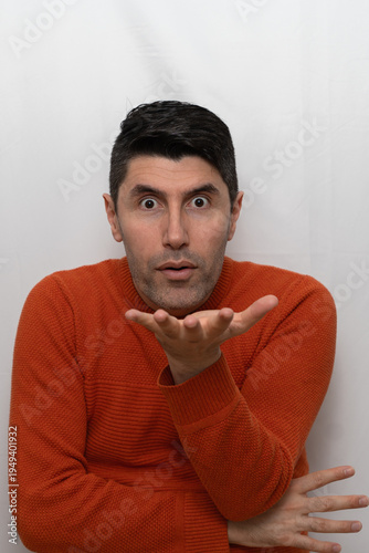 Wallpaper Mural Shocked man in orange sweater blowing a kiss or dust from his hand. Studio portrait of a man with an intense and surprised facial expression. Torontodigital.ca
