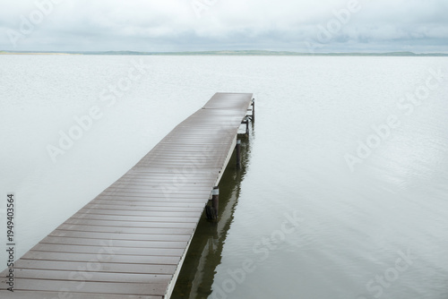 Canada, SK, Lloydminster, Manitou Lake.  Weathered wooden dock juts out into the still lake.