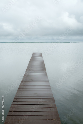 Canada, SK, Lloydminster, Manitou Lake.  Weathered wooden dock juts out into the still lake.