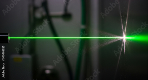 Green laser beam cutting through material with sparks flying.