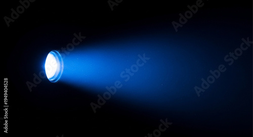 Bright blue spotlight beam illuminating darkness with light rays.