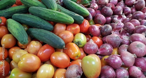 Foto Vibrant vegetable market scene in Kenya, Africa, featuring piles of red onions, red pelati tomatoes, and fresh green cucumbers