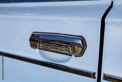 Canvas-taulu Close-up of a blue vintage car front: headlights, chrome grille and retro whitewall tires on a cobblestone road