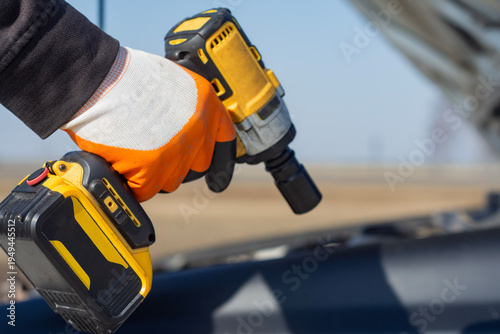 Valokuva Mechanic uses a battery powered power tool to fix a vehicle under an open hood