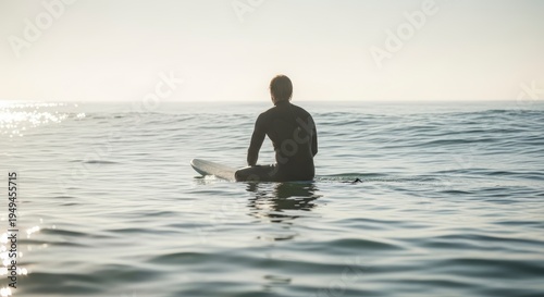 Man sitting on surfboard in ocean.