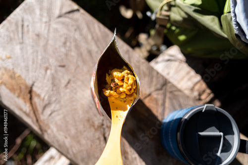 Hiker s freeze-dried meal on a plastic spoon over a food pouch.