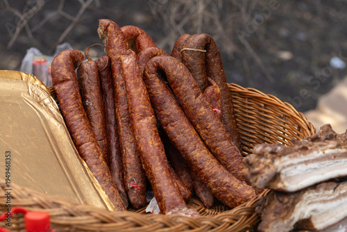 Photos Farmhouse salted smoked sausage in a wicker basket on the counter, farm food at