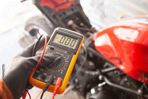 mechanic checking the voltage of a motorbike with a multimeter