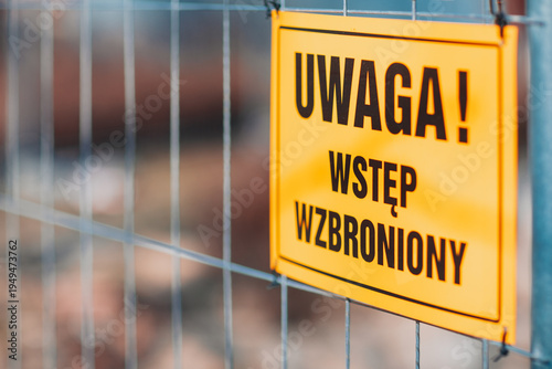 Yellow warning no entry sign attached to metal fence