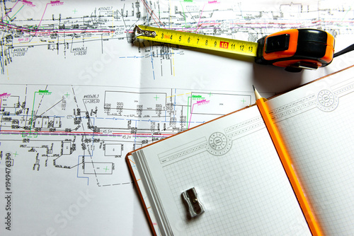 A sheet of construction drawings, a tape measure and a pencil