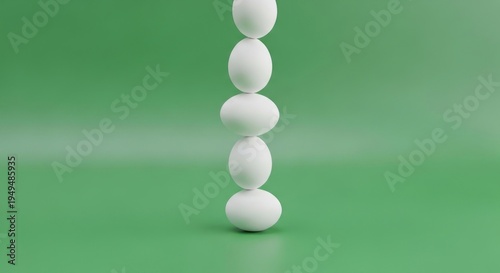 A stack of five white eggs standing upright on a green surface