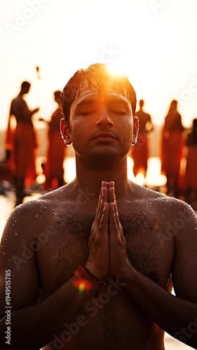 Hindu man praying in river during sunrise with hands clasped