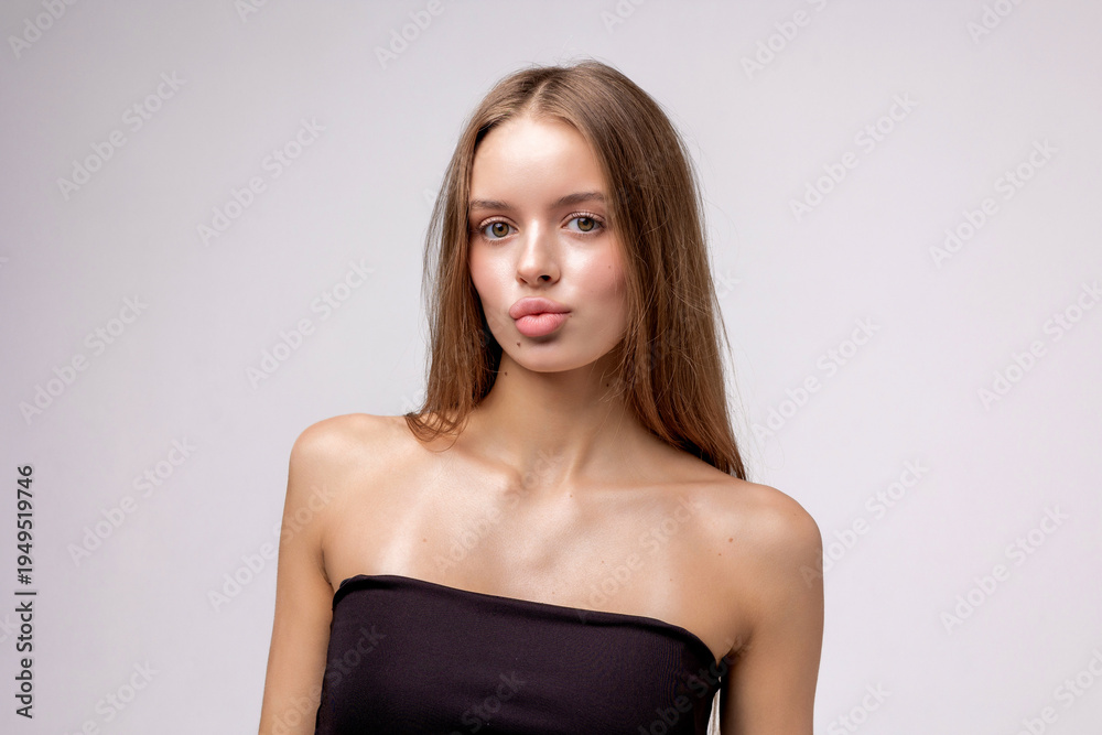 Fototapeta premium Young woman poses confidently in a studio with a plain background and minimalist style