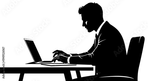 Silhouette of a businessman working on a laptop at a desk in a modern office