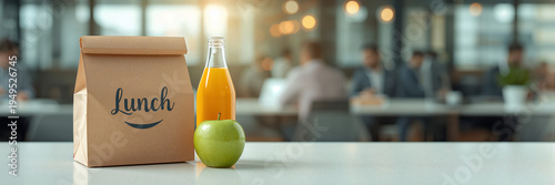 On the office desk is an eco-friendly paper bag with the text lunch , apple and a bottle of juice 