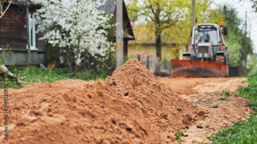 Canvas Print Bulldozer working on rural village road clearing soil for new infrastructure