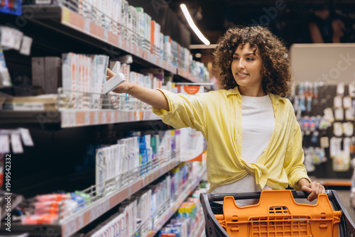 Woman choosing product from supermarket shelf, shopping for groceries and household items at retail store