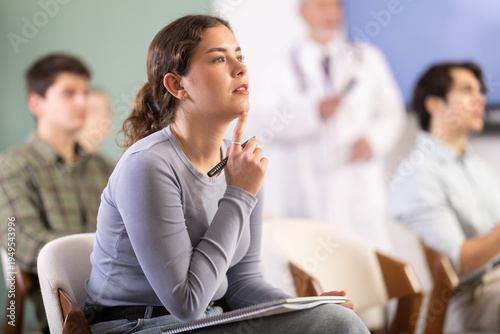 Fotografie Attentive young girl watching presentation during a university lesson with senio