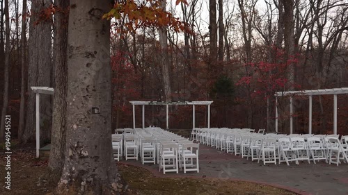 Outdoor woodland wedding ceremony with white chairs in autumn