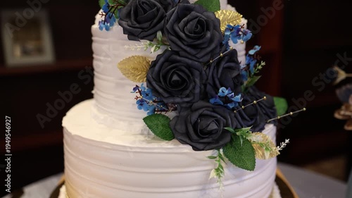 White wedding cake with navy roses and blue floral decor