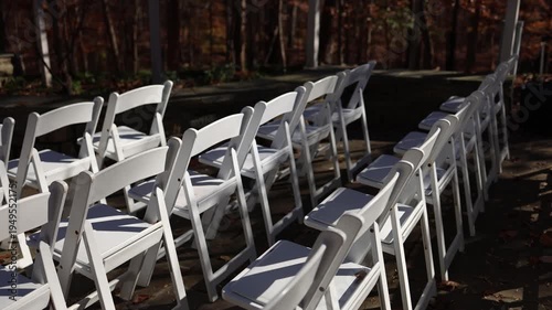 Outdoor ceremony setup with rows of white folding chairs