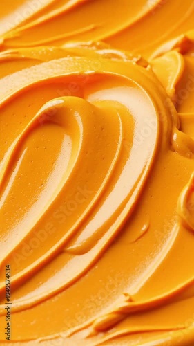 Close up of swirled bright orange cosmetic cream with smooth thick texture representing organic skincare product