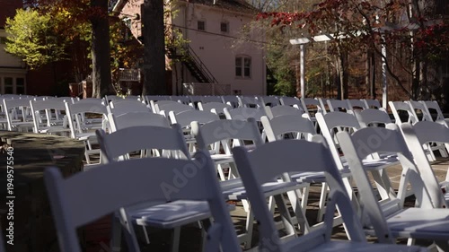 Outdoor wedding ceremony seating with white chairs and pergola