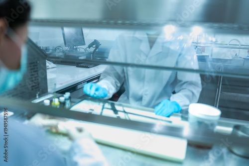 Obraz na płótnie Lab technician working behind glass sash of fume hood for safety