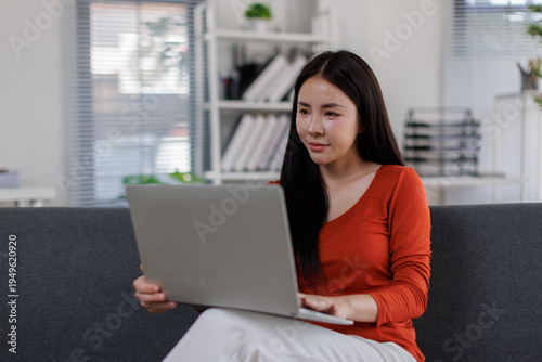 A calm and focused woman sitting on a sofa, working on her laptop, embodying concentration and dedication in a sleek and modern workspace. Free Download A calm and focused woman sitting on a sofa, working on her laptop, embodying concentration and dedication in a sleek and modern workspace. - GFXLoad