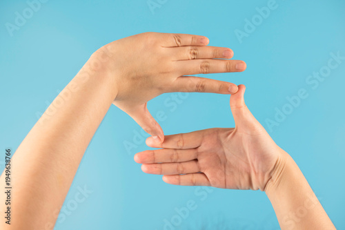 Close-up of two hands creating  rectangular frame shape with fingers, isolated on a bright blue background. Ideal for photography, vision, focus, and creative perspective concepts.