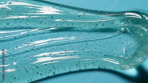 Clear cosmetic gel texture with air bubbles on blue background