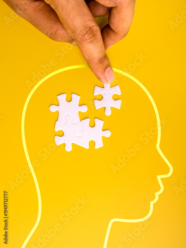 Mental health and problem solving concept with human hand placing puzzle piece inside head silhouette. Psychology therapy, idea solution, cognitive thinking, brain function and mental awareness.