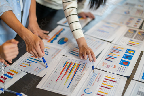 Close up of business consultant team hands pointing at data summary charts with pens on table, Corporate data analysts discussing financial strategy, market research and investment planning concept