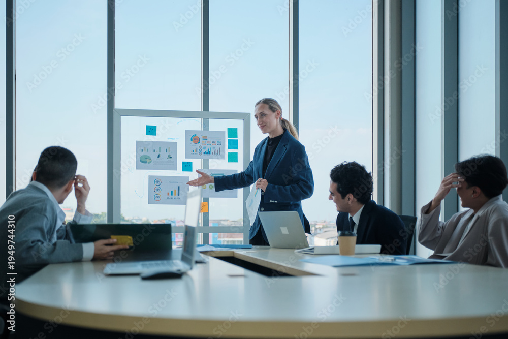 Fototapeta premium Young confident female company CEO explains finance and marketing investment analysis, discusses, and brainstorms with multiracial partnership team in meeting, business strategy report presentation.