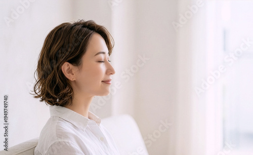 Peaceful Japanese middle-aged woman relaxing with eyes closed in bright room with copy space Free Download Peaceful Japanese middle-aged woman relaxing with eyes closed in bright room with copy space - GFXLoad