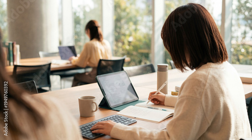Foto Dedicated young woman working efficiently with a tablet and notebook in a bright, contemporary office environment