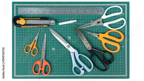 Craft tools and equipment including scissors a knife and a thread cutter. Place it on the green cutting mat. On isolated white background.