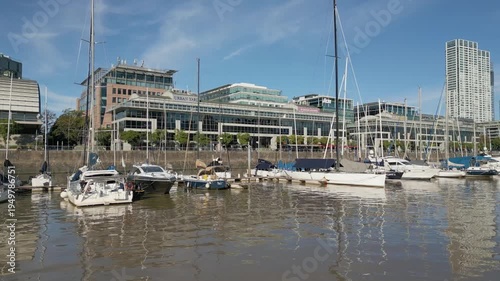 Boats docked in a harbor with city buildings in the background during daytime