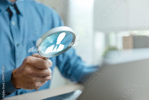 Fotografie Business professional holding magnifying glass with employee icon, symbolizing recruitment, candidate selection and talent acquisition