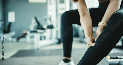 Fotografie Female athlete holding sore calf muscle after intense workout, representing delayed onset muscle soreness and post workout pain