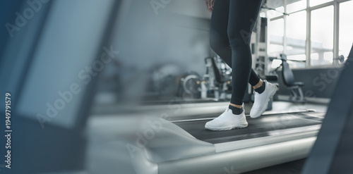Tableau sur toile Close up of woman walking on treadmill in modern gym with copy space, representing fitness background and healthy lifestyle concept