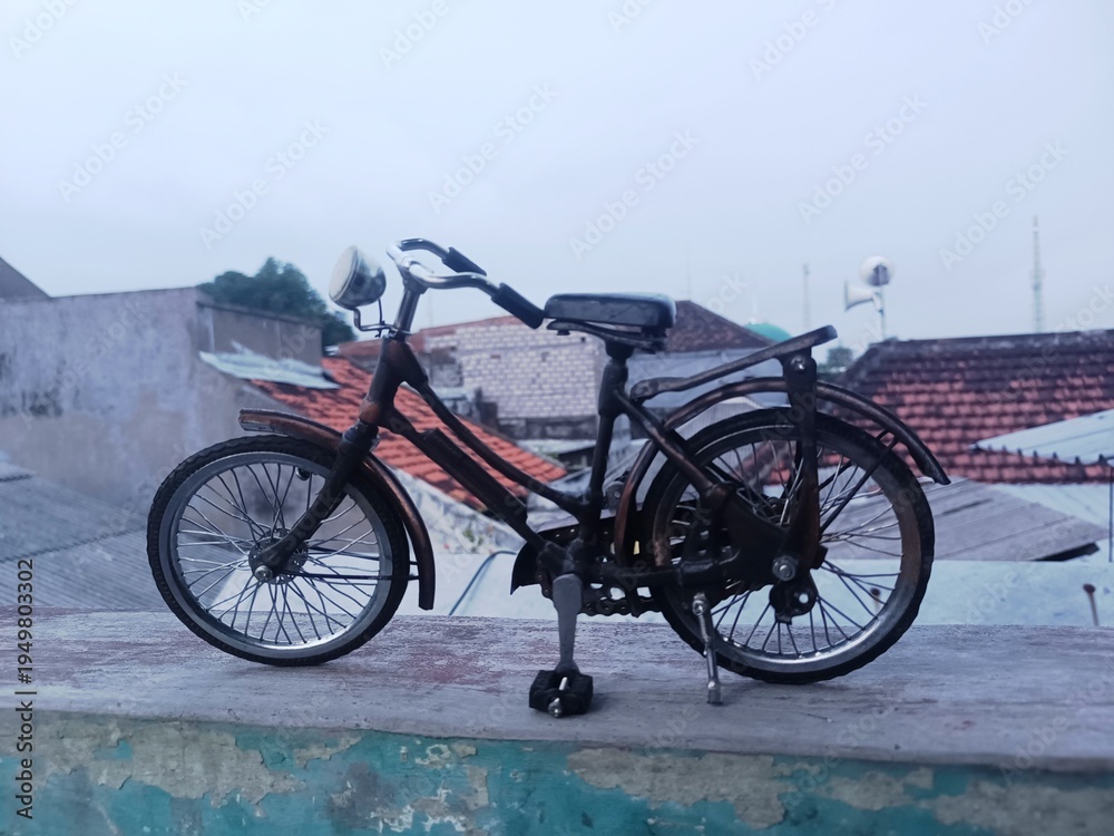 Fototapeta premium Miniature Vintage Bicycle on Rooftop with Urban Background